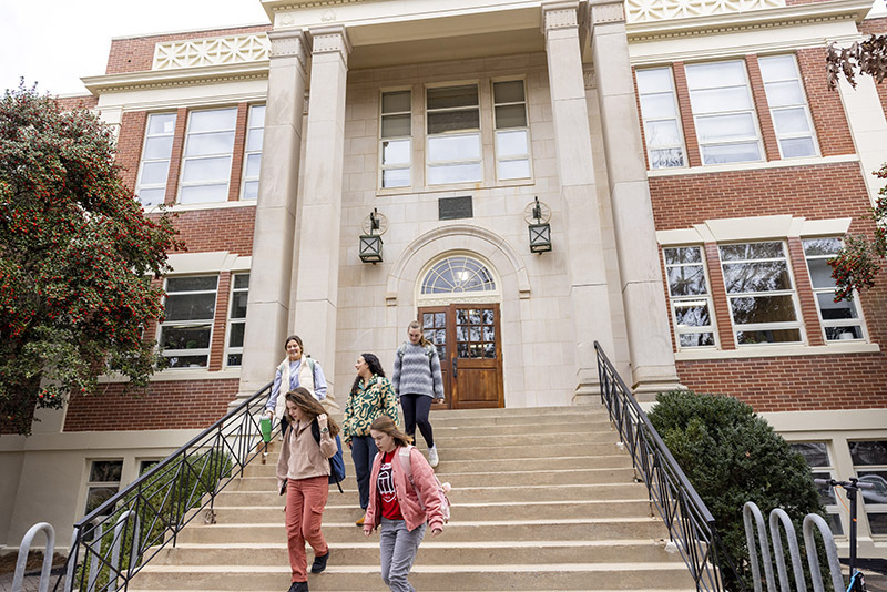 Collegiate building with students walking down the front stairs.