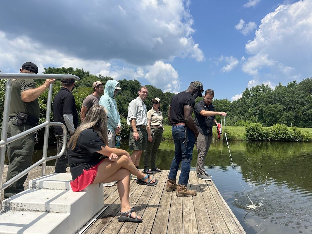 Group of people standing on a dock observing a secchi disk in a lake