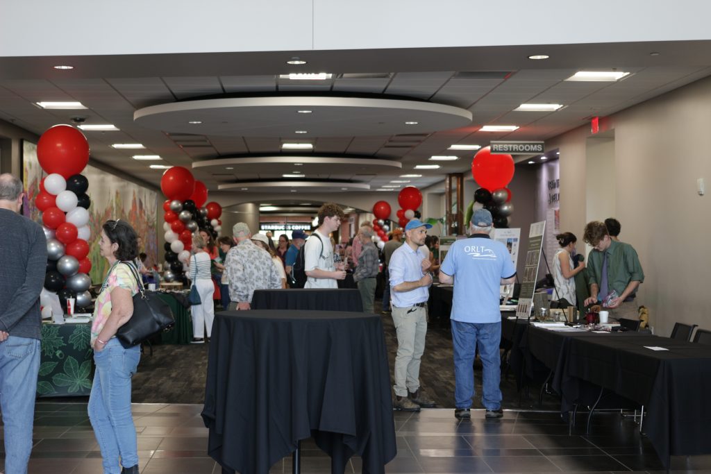 People gathered in a lobby festooned with red, black, white, and silver balloons.